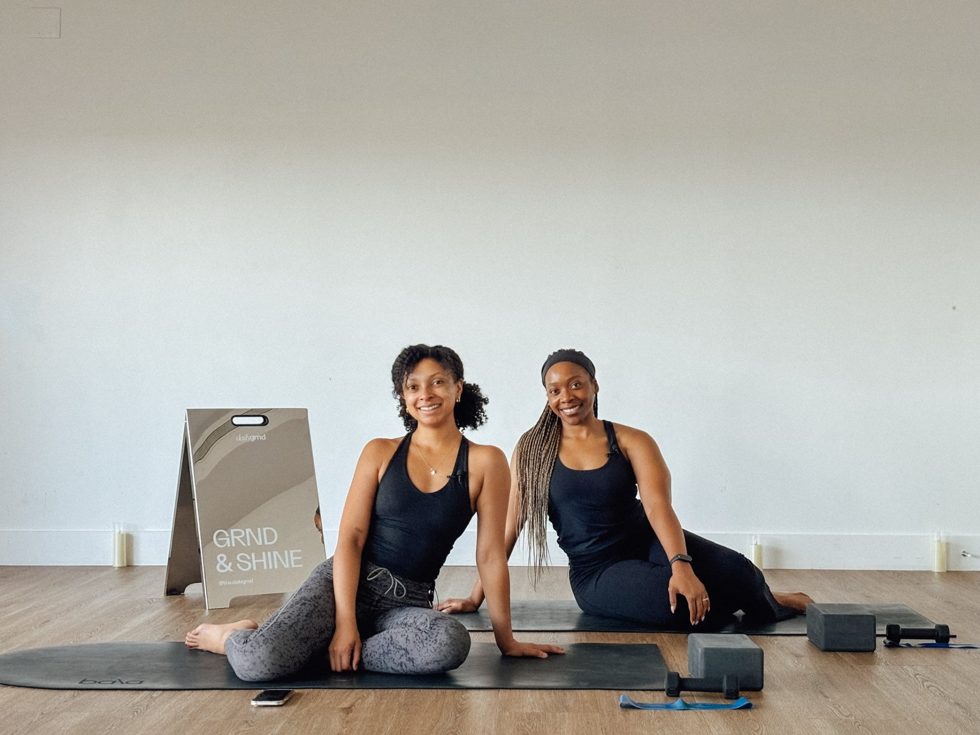 Founders Zay and Stacey smiling on their mats in the studio